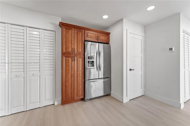 kitchen featuring stainless steel fridge, light wood-type flooring, baseboards, recessed lighting, and brown cabinetry
