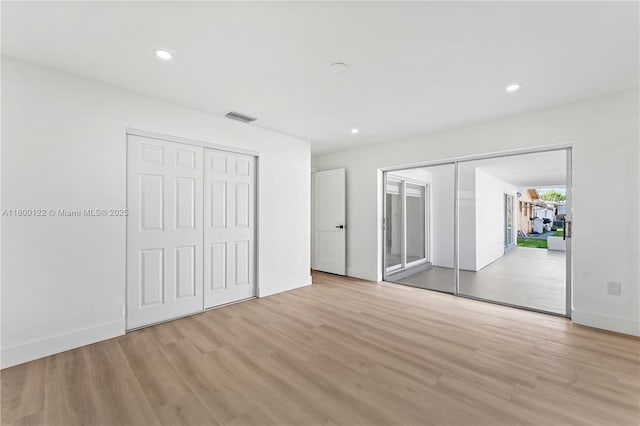 unfurnished bedroom featuring light wood-style floors, multiple closets, baseboards, and recessed lighting