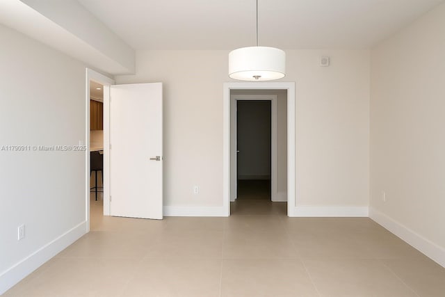 empty room featuring baseboards and light tile patterned floors