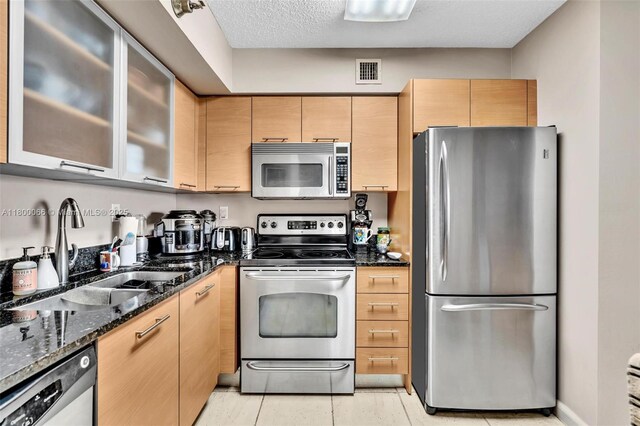 3300 NE 191st St Unit Lp04, Aventura, FL 33180 - kitchen featuring appliances with stainless steel finishes, a sink, dark stone countertops, glass insert cabinets, and light brown cabinets