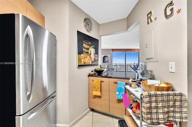 3300 NE 191st St Unit Lp04, Aventura, FL 33180 - kitchen with freestanding refrigerator, a textured ceiling, light tile patterned floors, baseboards, and dark countertops