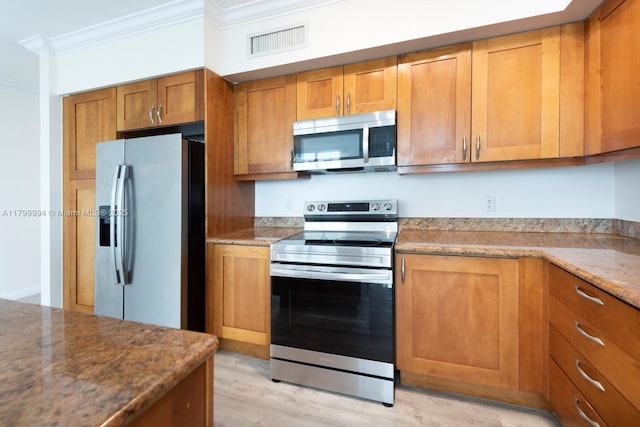 1745 E Hallandale Beach Blvd Unit 1903W, Hallandale Beach, FL 33009 - kitchen featuring stainless steel appliances, ornamental molding, brown cabinetry, light stone countertops, and light wood-type flooring