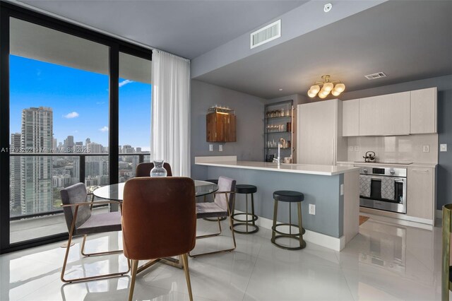 501 NE 31st St Unit 2906, Miami, FL 33137 - kitchen with stainless steel oven, a kitchen breakfast bar, a wall of windows, modern cabinets, and light countertops