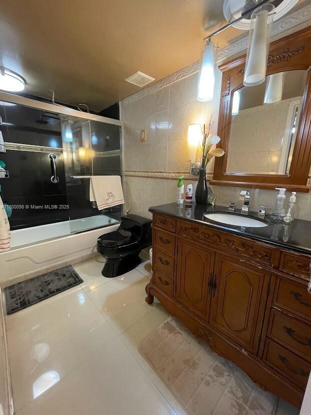 8360 Sands Point Blvd Unit G209, Tamarac, FL 33321 - full bathroom featuring shower / bath combination with glass door, vanity, toilet, tile patterned floors, and tile walls