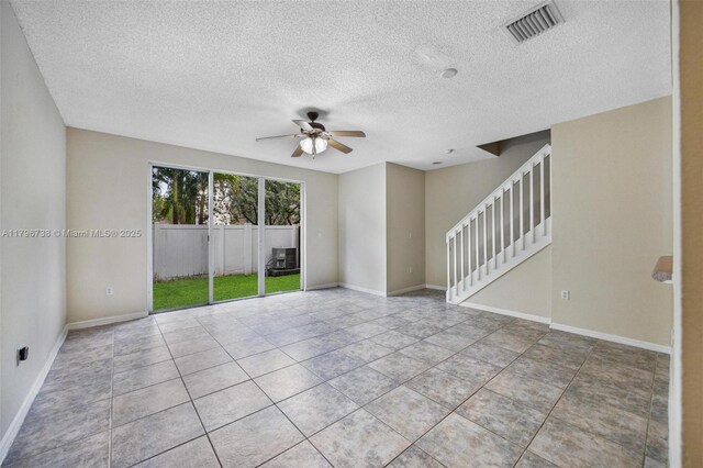 2252 NE 42nd Cir, Homestead, FL 33033 - unfurnished living room featuring a ceiling fan, a textured ceiling, stairway, tile patterned floors, and baseboards