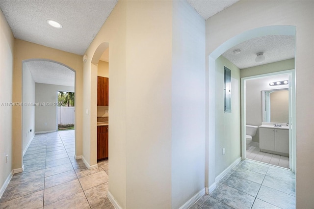2252 NE 42nd Cir, Homestead, FL 33033 - hall with a textured ceiling, arched walkways, light tile patterned flooring, baseboards, and a sink