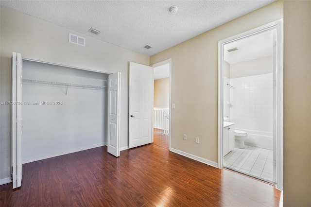 2252 NE 42nd Cir, Homestead, FL 33033 - unfurnished bedroom with wood finished floors, a closet, baseboards, connected bathroom, and a textured ceiling