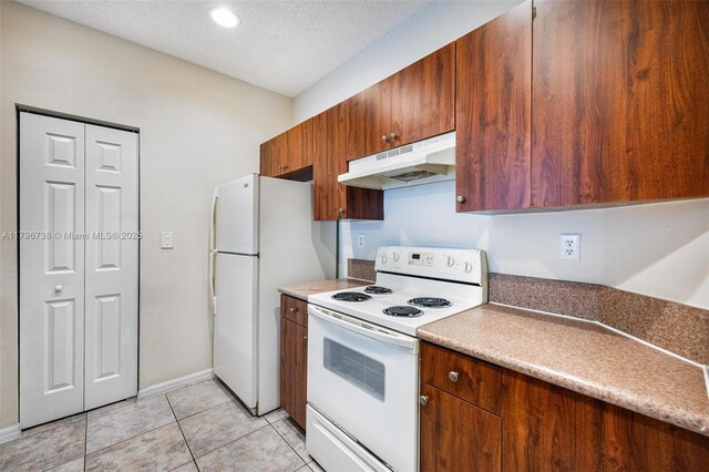 2252 NE 42nd Cir, Homestead, FL 33033 - kitchen featuring white appliances, under cabinet range hood, a textured ceiling, light tile patterned floors, and brown cabinetry