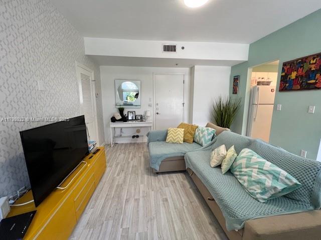 1614 Pennsylvania Ave Unit 2I, Miami Beach, FL 33139 - living room with wallpapered walls, light wood-style floors, and an accent wall