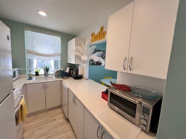1614 Pennsylvania Ave Unit 2I, Miami Beach, FL 33139 - kitchen with white appliances, a sink, light countertops, light wood-style floors, and recessed lighting