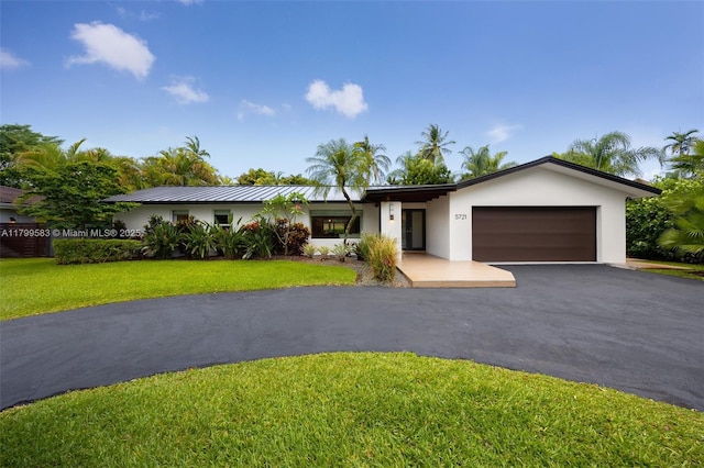 ranch-style house featuring stucco siding, asphalt driveway, a garage, and a front lawn