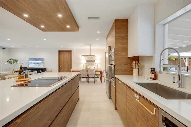 kitchen with modern cabinets, a sink, brown cabinets, black electric cooktop, and recessed lighting