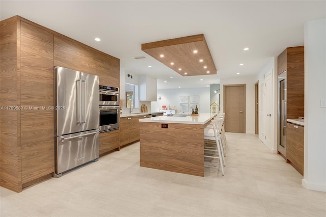kitchen featuring stainless steel appliances, light countertops, a center island, modern cabinets, and recessed lighting