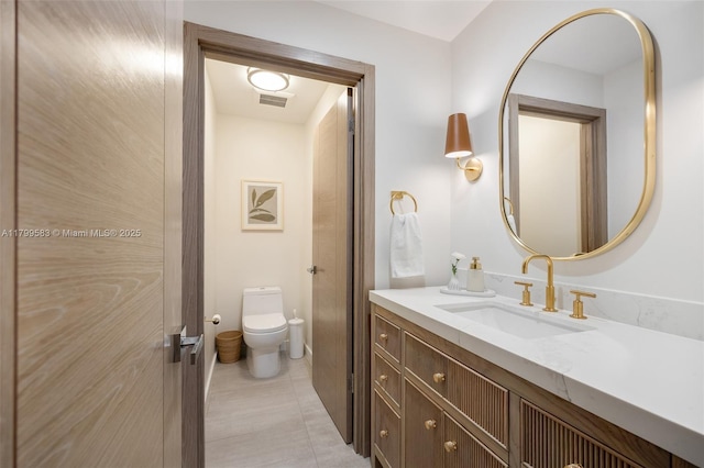 bathroom with toilet, vanity, and tile patterned flooring