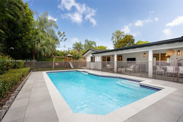 view of pool with fence, a playground, and a patio area