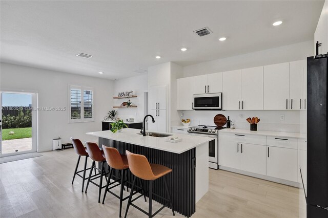 14836 SW 162nd St, Miami, FL 33187 - kitchen with white microwave, stainless steel stove, freestanding refrigerator, light wood-type flooring, and a breakfast bar area