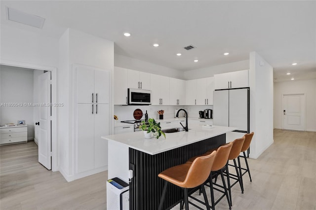 14836 SW 162nd St, Miami, FL 33187 - kitchen featuring light wood-type flooring, a breakfast bar, light countertops, white cabinetry, and recessed lighting