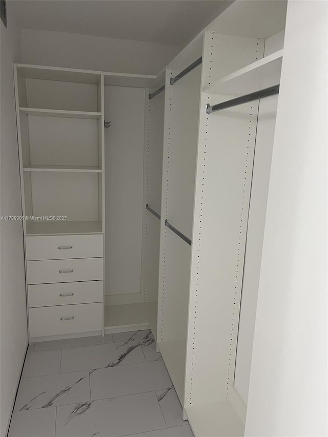 walk in closet with light marble finish floors