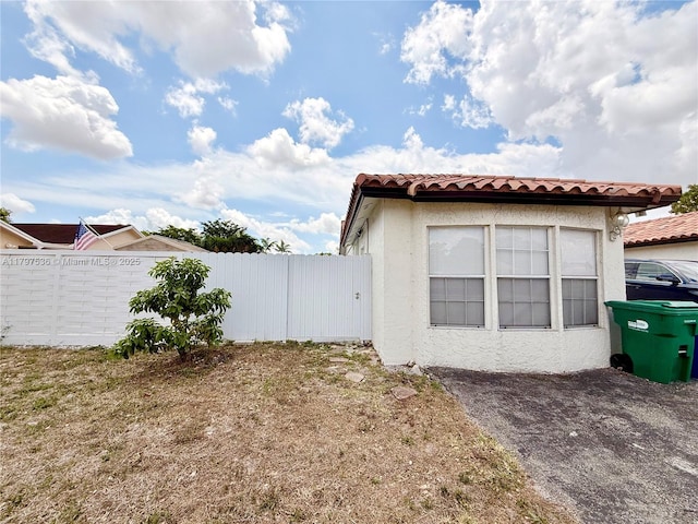 5730 NW 199th St, Hialeah, FL 33015 - view of side of property featuring fence, a tile roof, and stucco siding