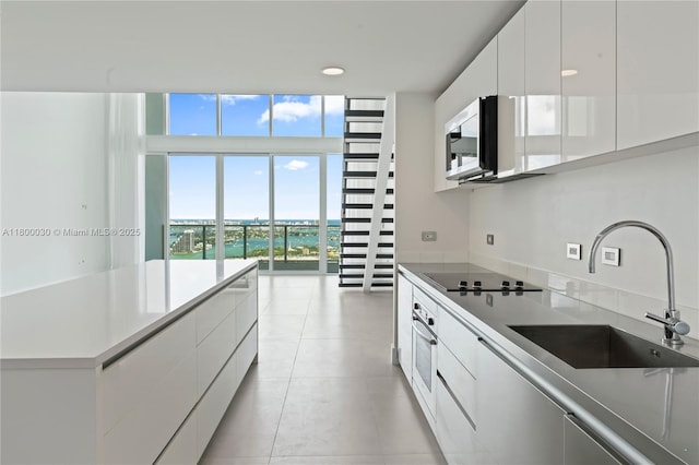 1040 Biscayne Blvd Unit 3802, Miami, FL 33132 - kitchen with a sink, black electric cooktop, stainless steel microwave, modern cabinets, and white cabinetry