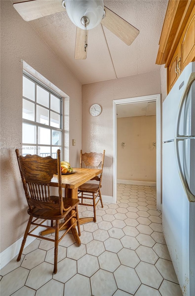 dining room with ceiling fan, light floors, a textured ceiling, and a textured wall
