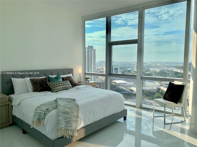 bedroom with a wall of windows, multiple windows, a city view, and tile patterned floors