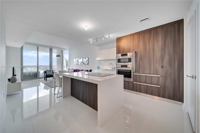 kitchen featuring modern cabinets, light tile patterned flooring, light countertops, a kitchen island, and expansive windows