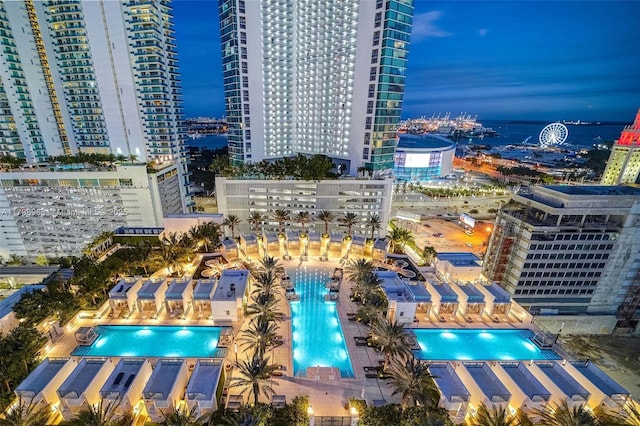 aerial view at twilight of view of pool area and a view of city lights