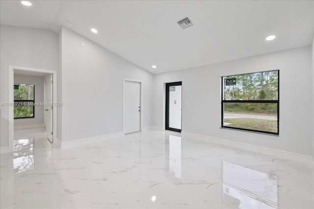 empty room featuring lofted ceiling, recessed lighting, baseboards, and light marble finish flooring