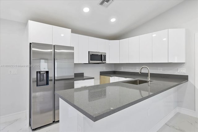 kitchen with appliances with stainless steel finishes, a sink, light marble finish floors, a peninsula, and baseboards