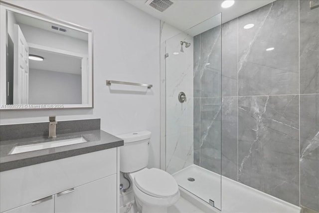 bathroom with toilet, a marble finish shower, and vanity