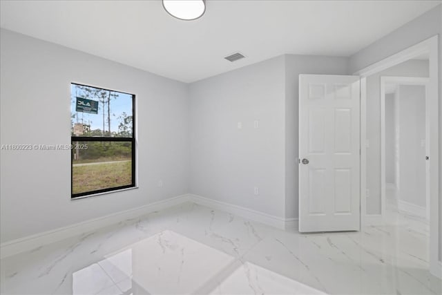 empty room featuring baseboards and marble finish floors