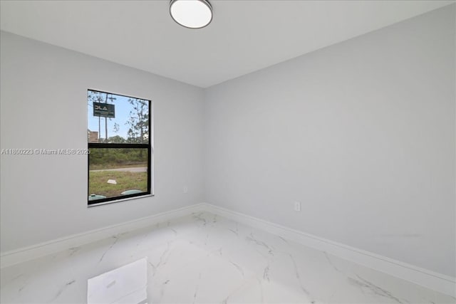 spare room featuring marble finish flooring and baseboards