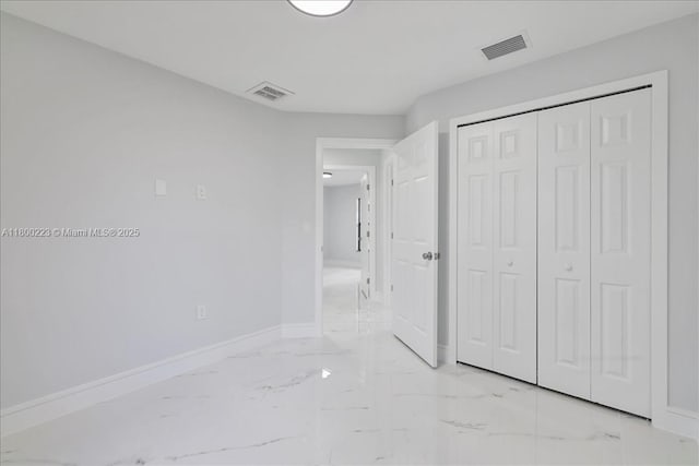 unfurnished bedroom with light marble finish floors, baseboards, and a closet
