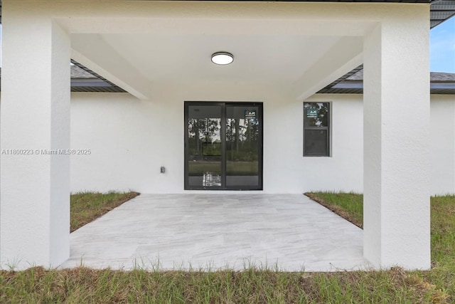 entrance to property featuring stucco siding and a patio