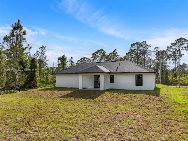 631 S Summit Ave, Lehigh Acres, FL 33974 - back of house featuring a lawn and stucco siding