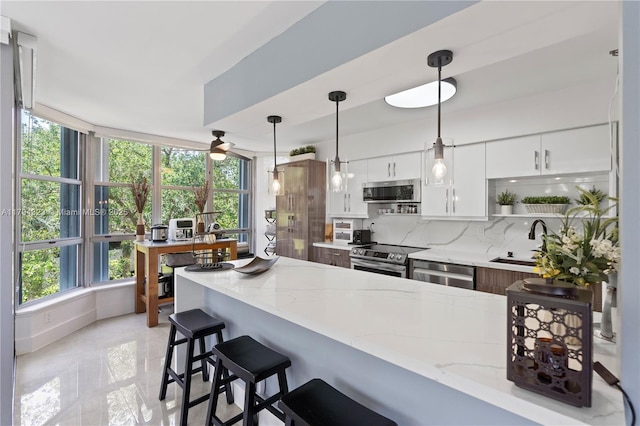 3600 Mystic Pointe Dr Unit 306, Aventura, FL 33180 - kitchen with stainless steel appliances, a sink, a kitchen bar, tasteful backsplash, and a peninsula