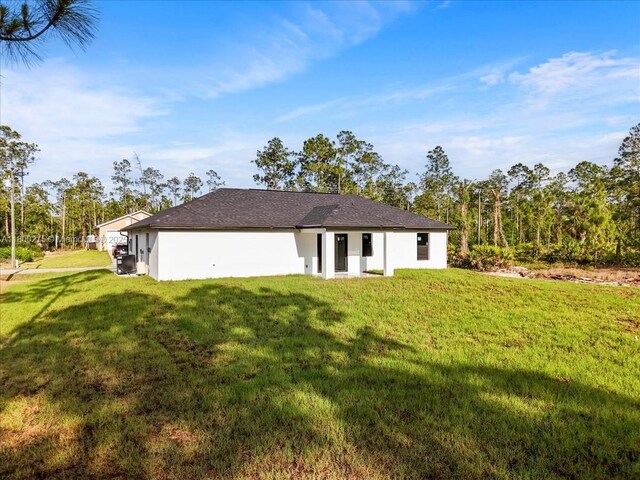 817 Moore Ave, Lehigh Acres, FL 33972 - rear view of property featuring a lawn and stucco siding
