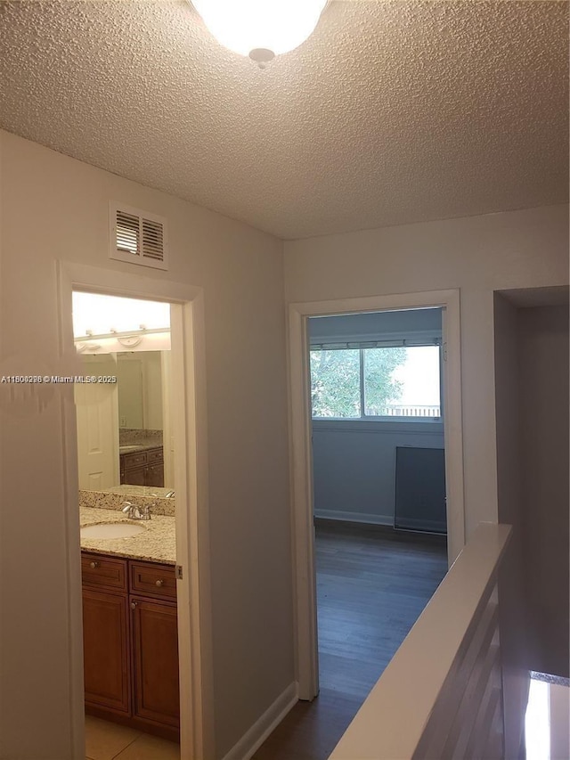 2520 Van Buren St Unit 7, Hollywood, FL 33020 - hall with light wood-style floors, a textured ceiling, a sink, and baseboards