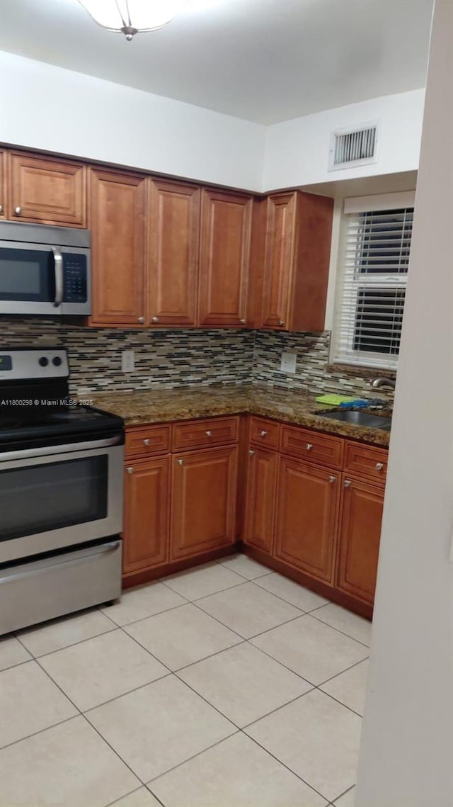 2520 Van Buren St Unit 7, Hollywood, FL 33020 - kitchen with stainless steel appliances, decorative backsplash, a sink, dark stone countertops, and brown cabinets