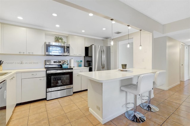 kitchen with appliances with stainless steel finishes, light tile patterned flooring, light countertops, a breakfast bar area, and recessed lighting