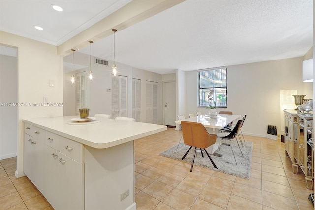 kitchen featuring light tile patterned floors, light countertops, decorative light fixtures, a peninsula, and baseboards