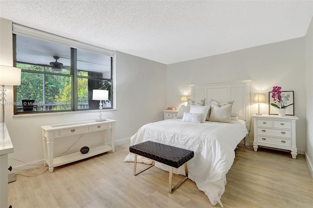 bedroom featuring light wood-style flooring, baseboards, and a textured ceiling