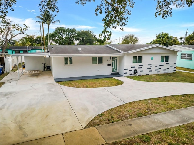view of front facade with driveway, stucco siding, a carport, and a front lawn