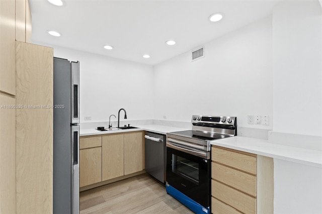6900 Bay Dr Unit 10I, Miami Beach, FL 33141 - kitchen with light brown cabinets, appliances with stainless steel finishes, a sink, light wood-style flooring, and recessed lighting