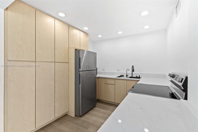 6900 Bay Dr Unit 10I, Miami Beach, FL 33141 - kitchen with freestanding refrigerator, a sink, light brown cabinets, light wood-style flooring, and light stone countertops