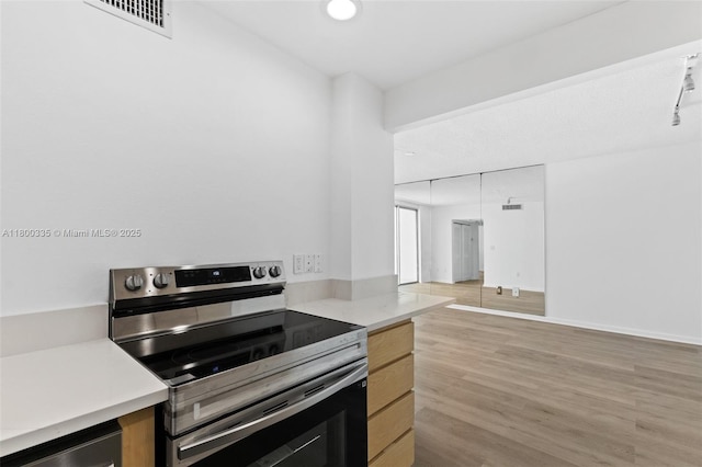 6900 Bay Dr Unit 10I, Miami Beach, FL 33141 - kitchen featuring stainless steel range with electric stovetop, light wood finished floors, light countertops, baseboards, and recessed lighting
