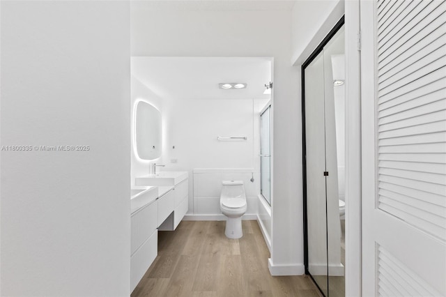 6900 Bay Dr Unit 10I, Miami Beach, FL 33141 - bathroom featuring toilet, wood finished floors, vanity, and enclosed tub / shower combo
