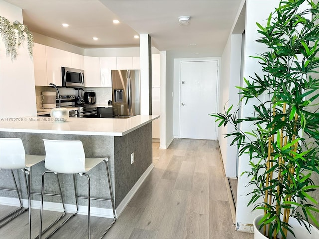 3731 N Country Club Dr Unit 2228, Aventura, FL 33180 - kitchen with stainless steel appliances, light countertops, light wood-style floors, white cabinetry, and a peninsula