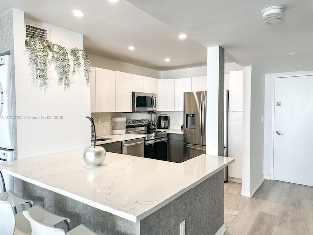 3731 N Country Club Dr Unit 2228, Aventura, FL 33180 - kitchen featuring appliances with stainless steel finishes, a peninsula, light wood-style floors, recessed lighting, and a breakfast bar